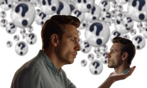 Selbstreflexion - Erkenne Dich selbst. Ein Mann betrachtet seinen eigenen Kopf den er in der Hand hält als Zeichen der Selbstreflexion